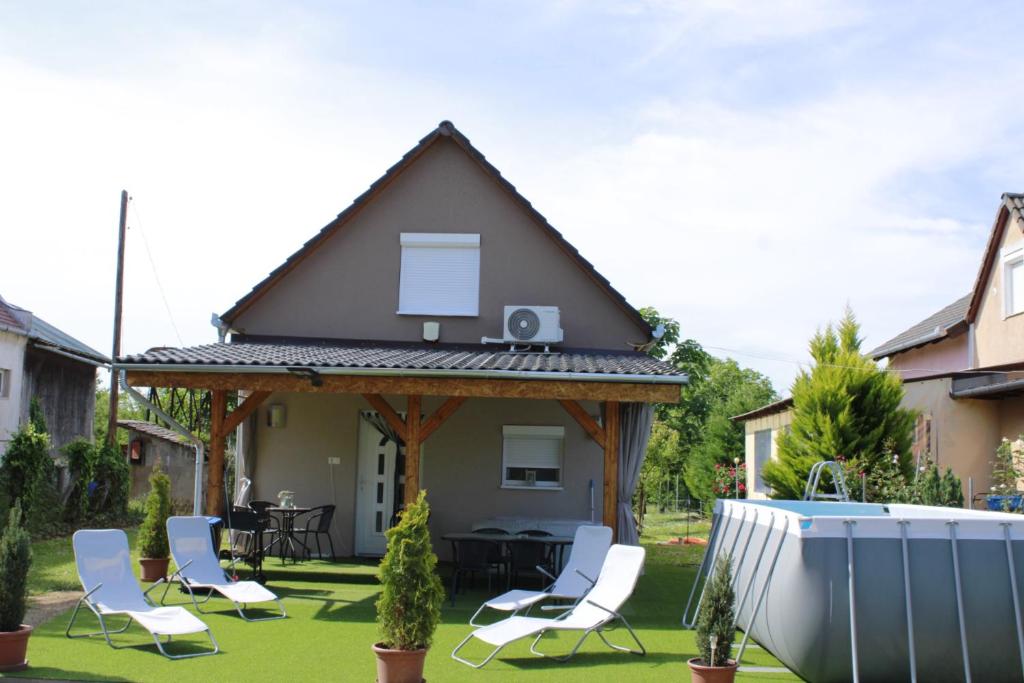 a house with a gazebo with chairs and a tub at Bíbic Vendégház in Kaposvár