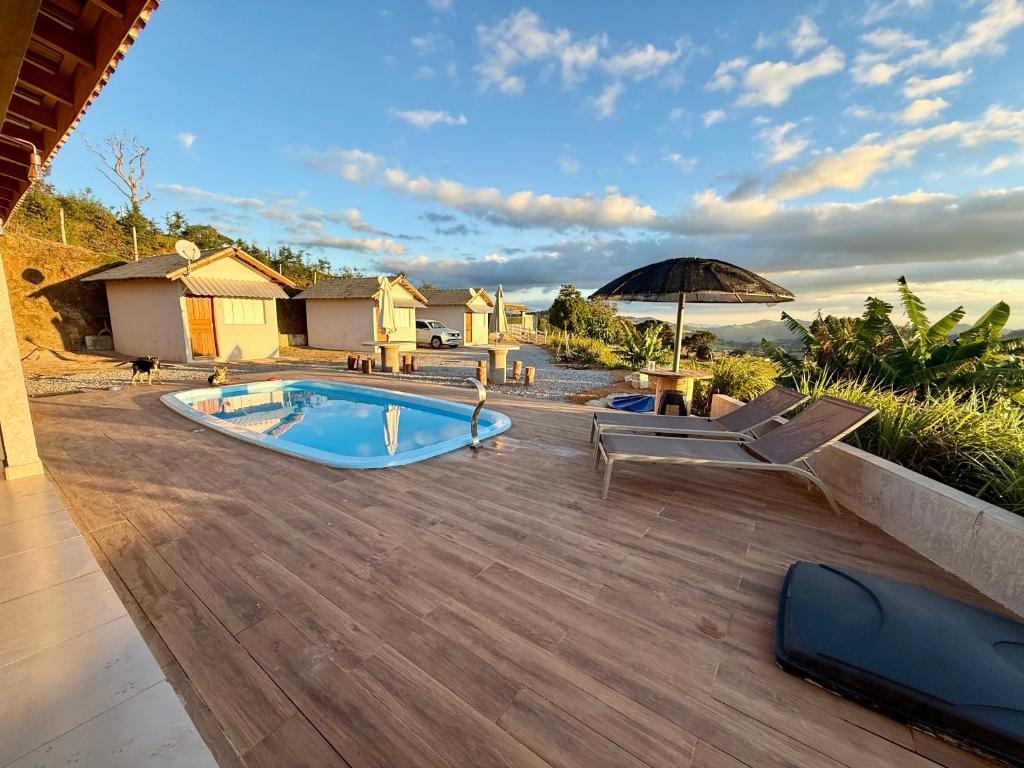 a backyard with a swimming pool and an umbrella at Chalés Sonho Meu in Munhoz