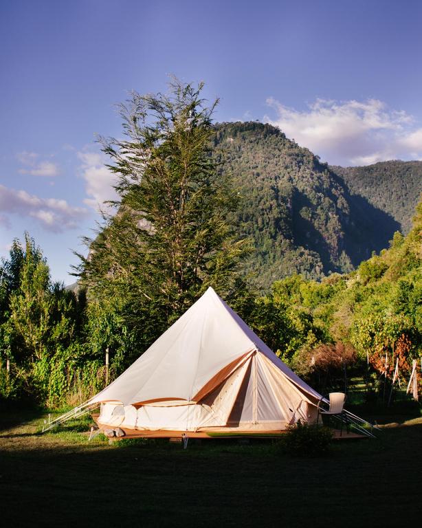 a white tent in front of a mountain at Amanecer Glamping in llifen