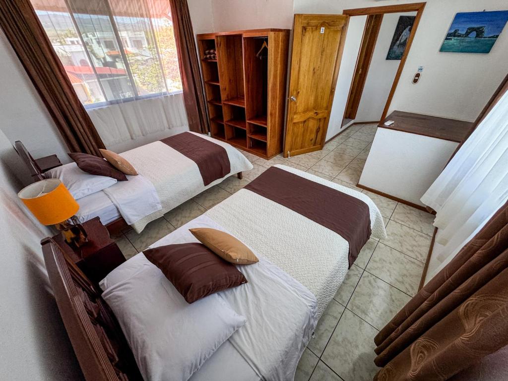 a hotel room with two beds and a window at Maytenus Galapagos in Puerto Ayora