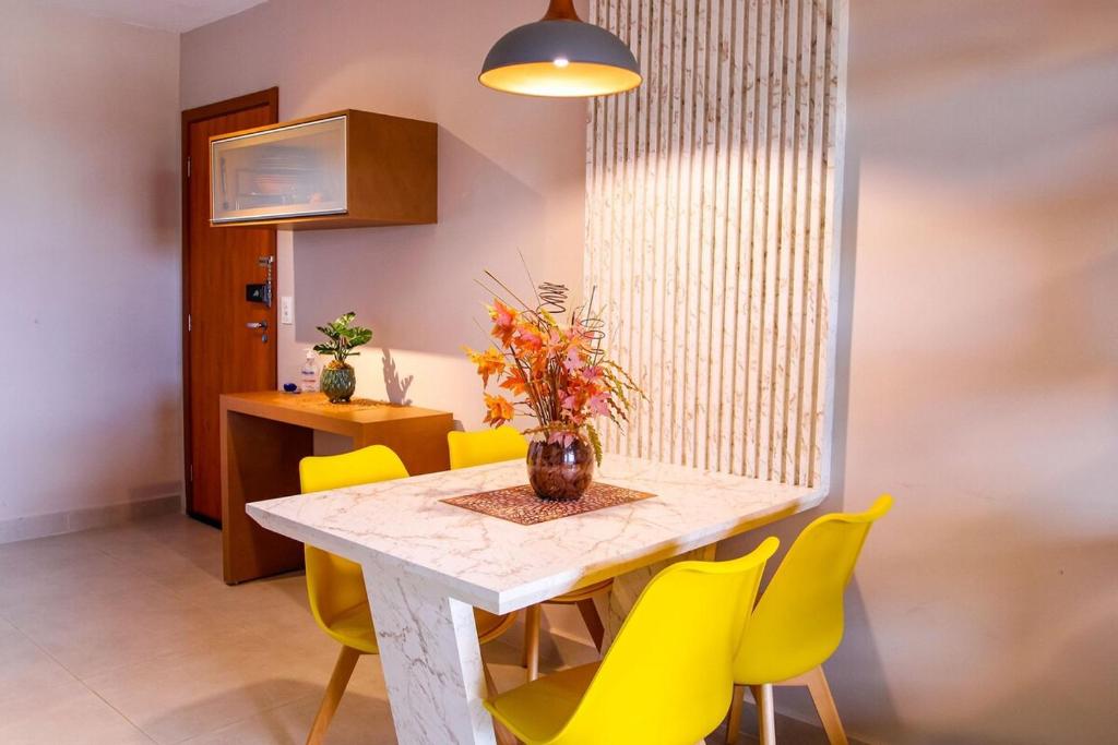 a dining room with a table and yellow chairs at Apartamento sofisticado, confortável e bem equipado - Loft Felau in Cuiabá
