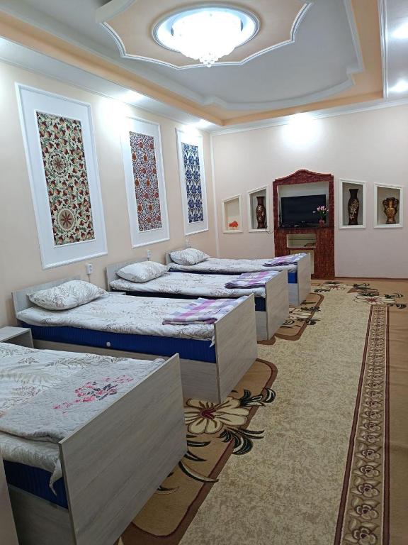 a row of beds in a room with a room with at Orzu Guest House in Bukhara