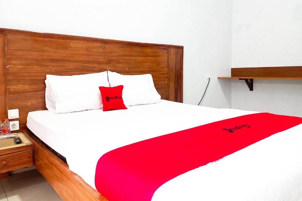 a bedroom with a bed with a red blanket on it at RedDoorz Plus Syariah at Umyas Hotel near Terminal Anjuk Ladang Nganjuk in Nganjuk