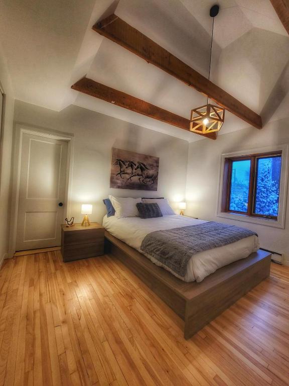 a bedroom with a large bed and wooden floors at La Pergola-3 in Quebec City