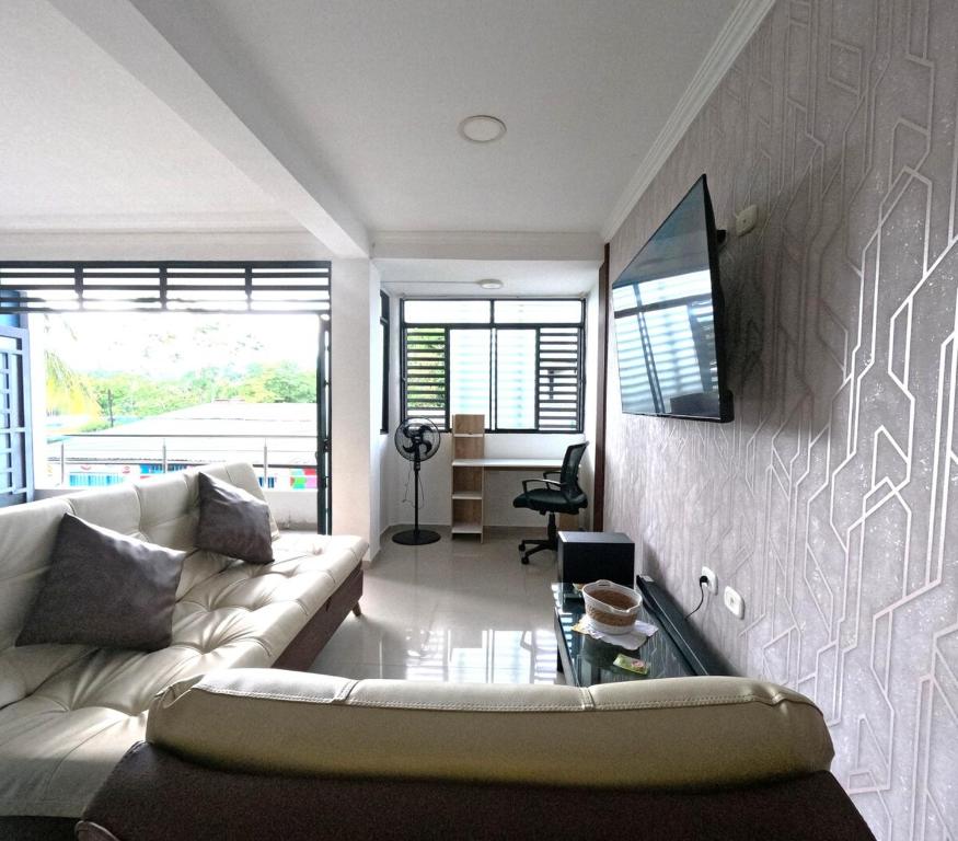 a living room with a couch and a tv on a wall at Nuevo y Confortable Apartamento in Florencia