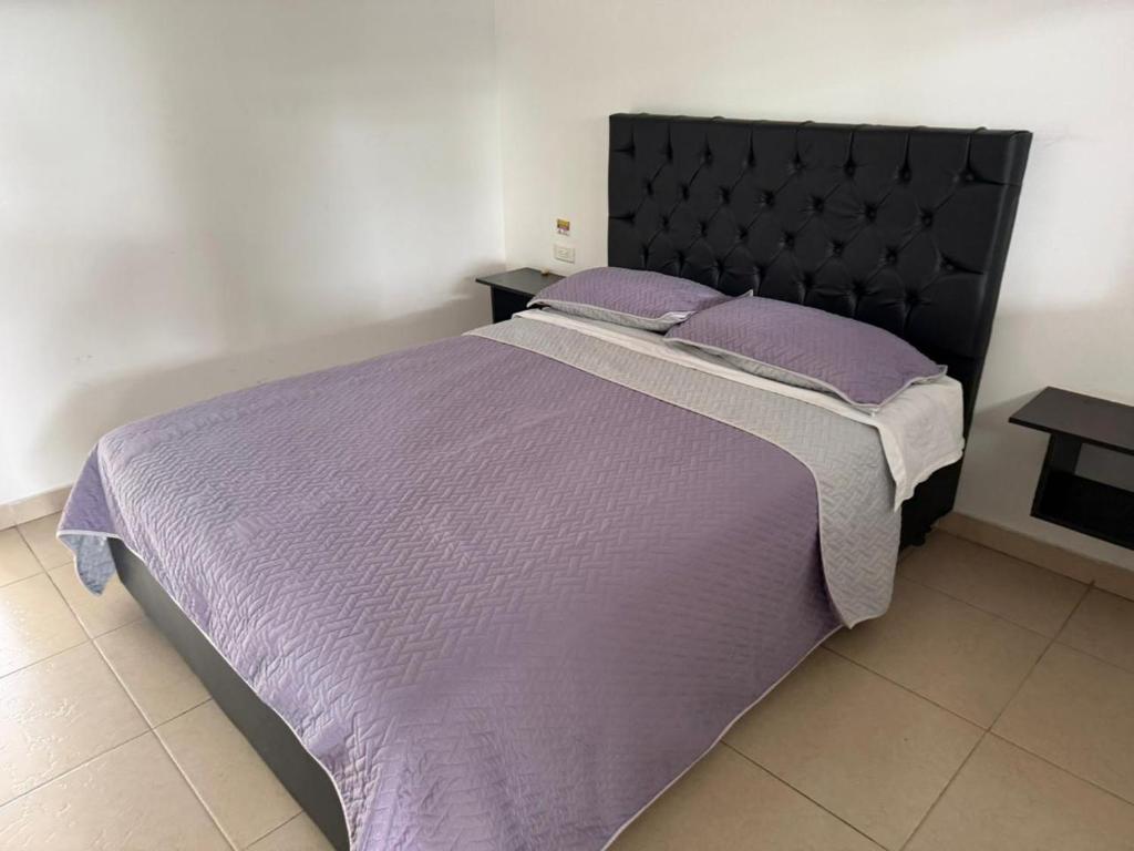 a bedroom with a large bed with purple sheets and pillows at HOTEL DEL MINERO Otanche in Otanche
