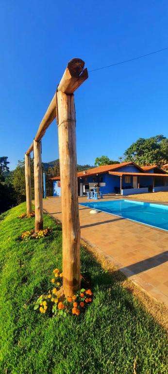 a bird perched on top of a wooden pole in the grass at Casinha Virtuosa in Monte Sião