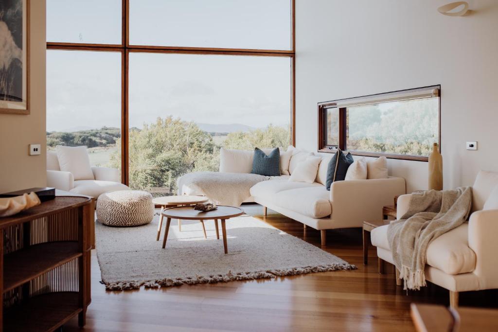 a living room with white furniture and a large window at Miramar Beach House in Seymour