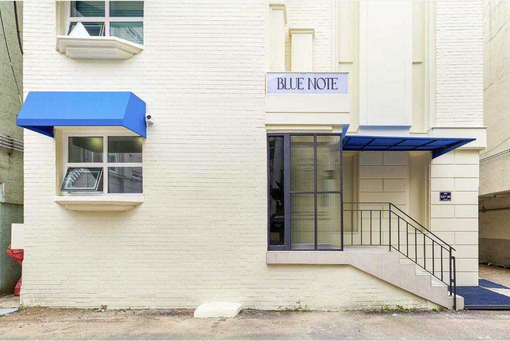 a white building with a blue awning on it at Blue Note in Incheon