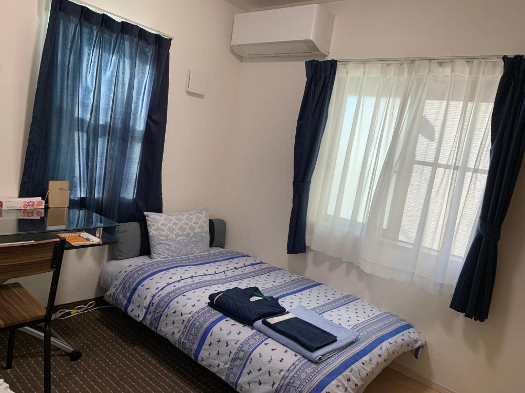 a bedroom with a bed and a desk and a window at Bessalov Home 1st room friendly house in Tokyo