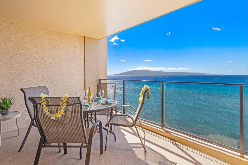 a balcony with a table and chairs and the ocean at Mahana 718 in Lahaina