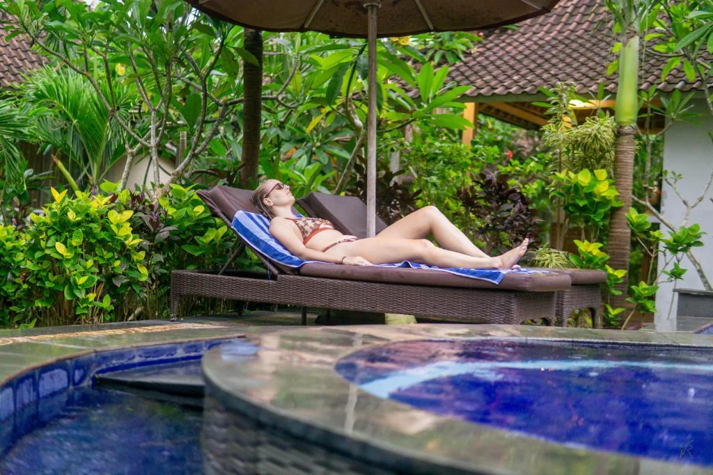 a woman laying on a chair next to a swimming pool at The Lucky Cottage in Nusa Lembongan
