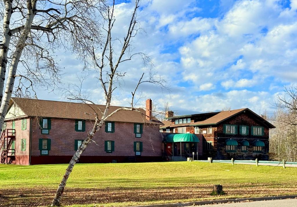 a large brick building with a grass field in front at Riverview Lodge in Dryden