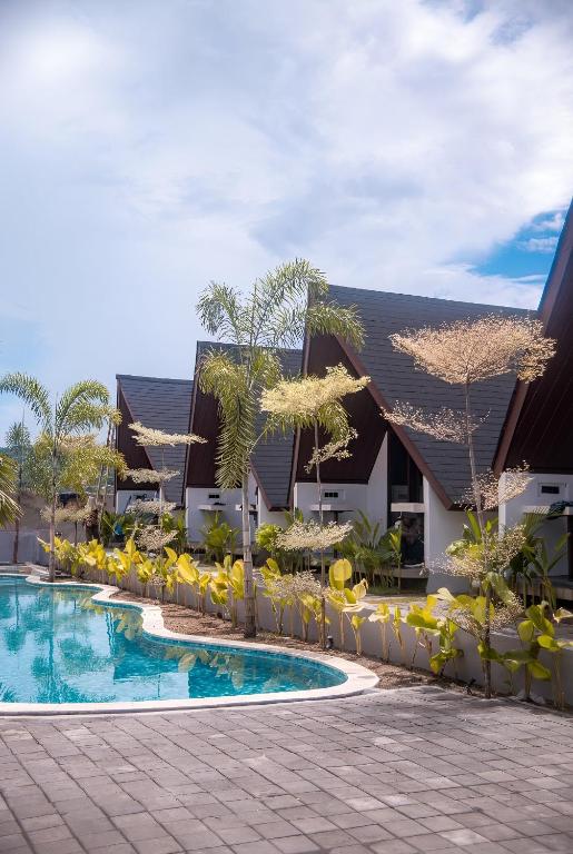 a resort with a swimming pool and yellow chairs at Limbo Lux Bungalows in Kuta Lombok