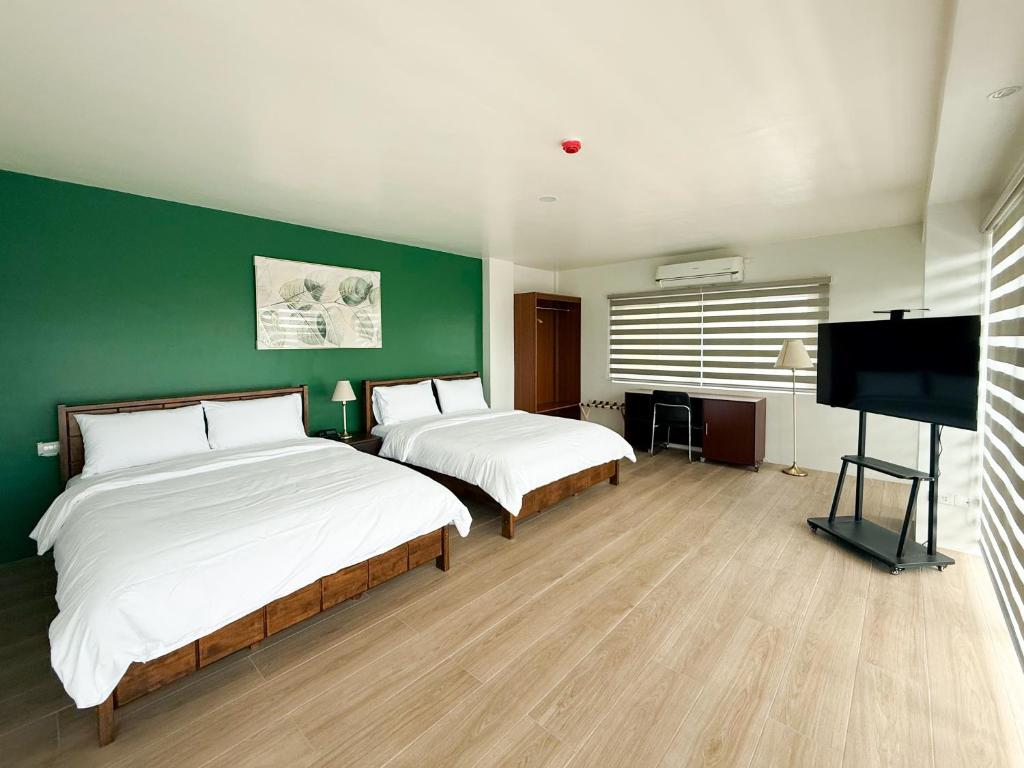 a bedroom with two beds and a flat screen tv at The Nest Bed and Breakfast - Kalibo in Kalibo