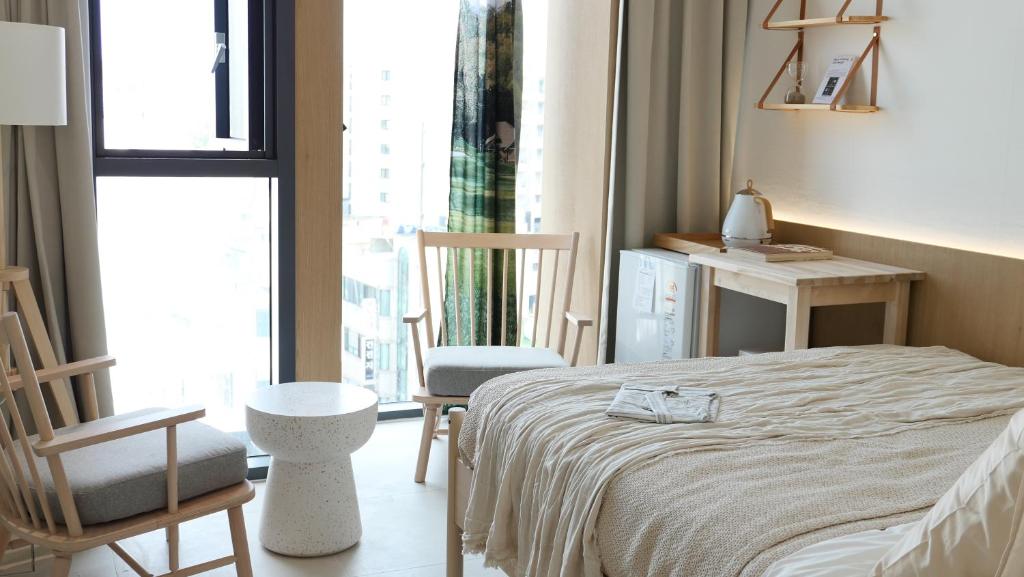 a bedroom with a bed and two chairs and a window at 제주 디스피어 호텔 D-Sphere in Jeju