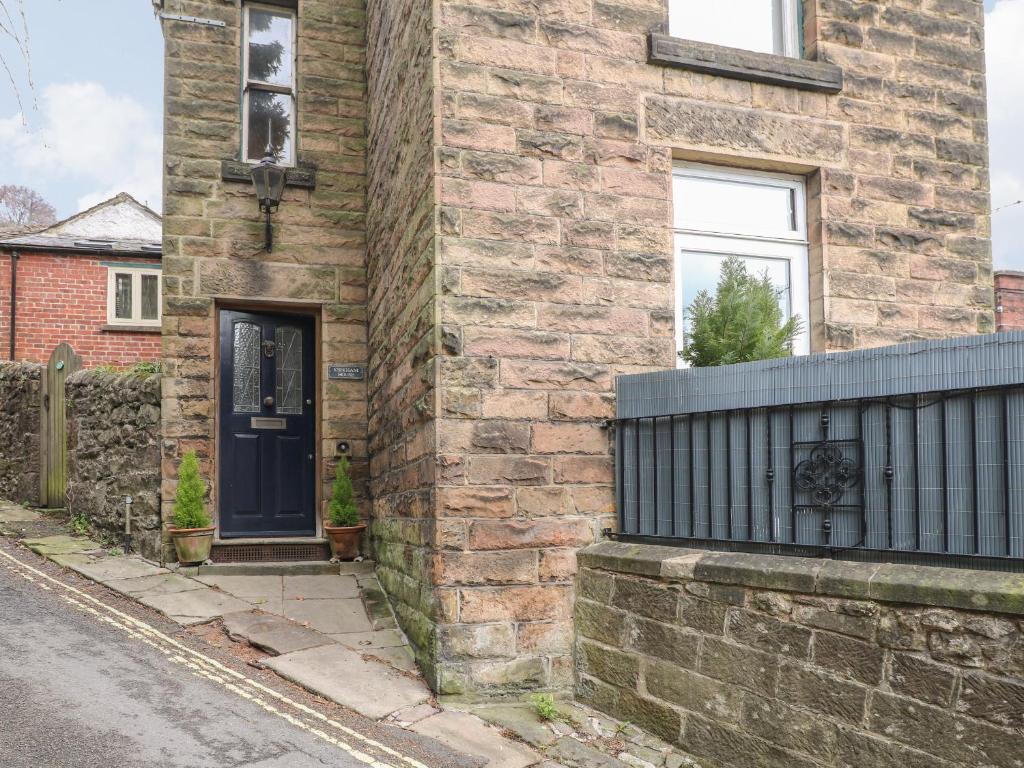 a brick house with a blue door on a street at Kirkham House in Matlock