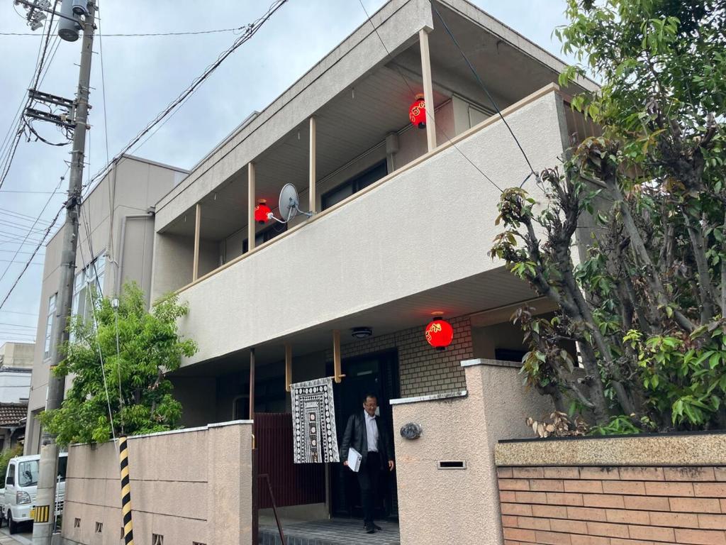 a man walking into a building with a sign on it at 丸亀 Sawai 一棟貸し 丸亀駅徒歩 10人まで宿泊可能 駐車場2台有 子供部屋ベビーベッド有 in Marugame