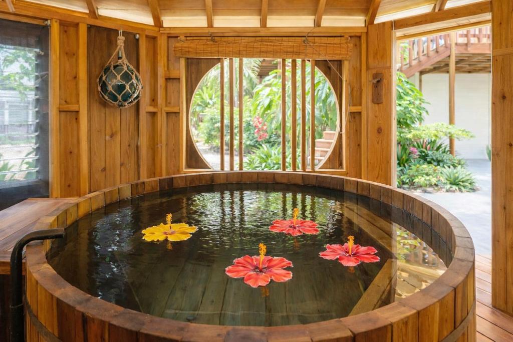 a bathtub with four colorful flowers in the water at Island Breeze - Round House with BBQ - Wooden Hot Tub - Beach in Onna