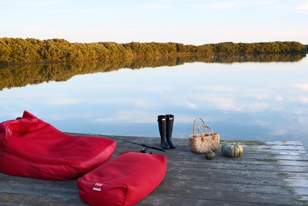 a red blanket and boots on a dock near a body of water at Bloom by the Bend in Tooradin