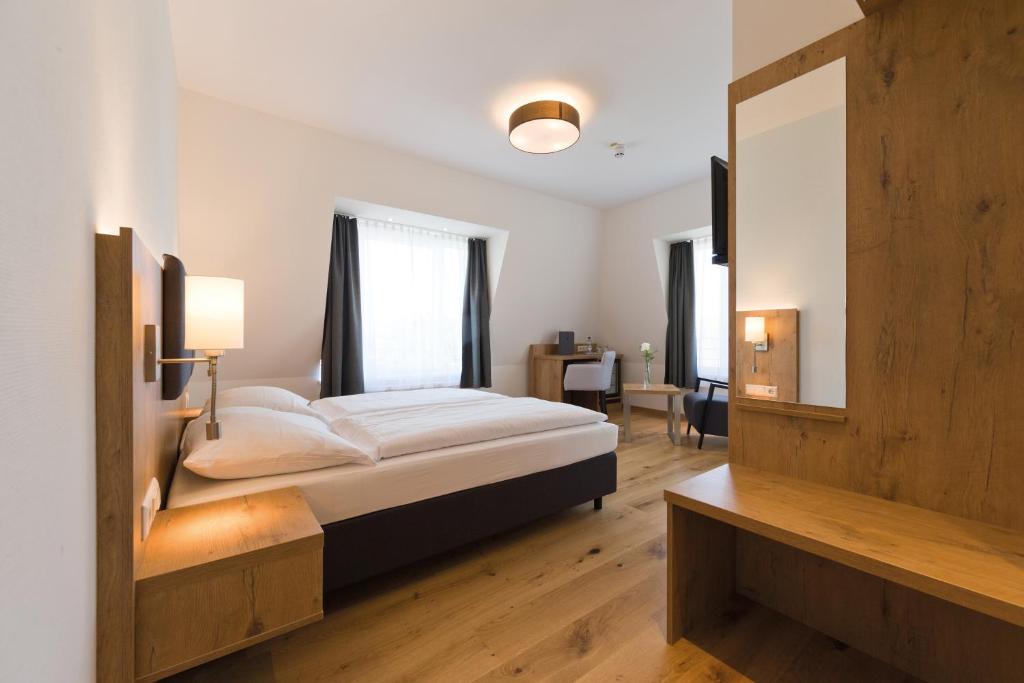 a bedroom with a large bed and a mirror at Adler Hotel & Gasthaus in Nonnenhorn