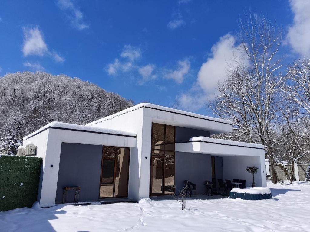 una casa blanca con nieve en el suelo en Harmony Hideaway Gabala, en Gabala
