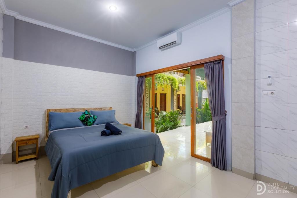 a bedroom with a blue bed and a sliding glass door at Bali DD homestay seminyak in Seminyak