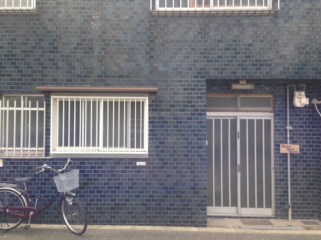 uma bicicleta estacionada em frente a um edifício de tijolos azuis em Peace house Abeno em Osaka