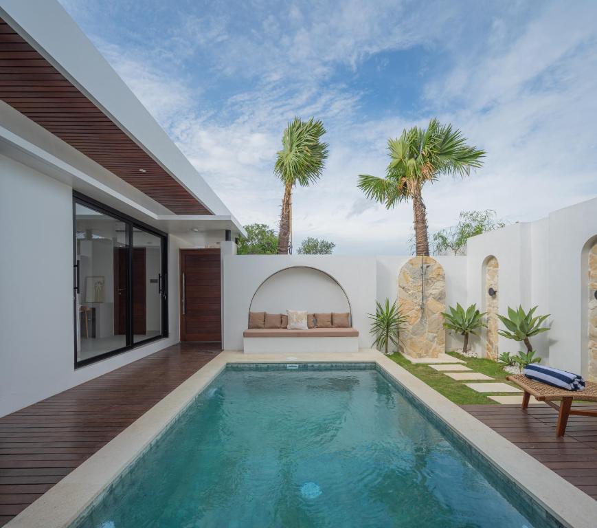 a swimming pool in the backyard of a house with palm trees at Monstera Uluwatu in Uluwatu