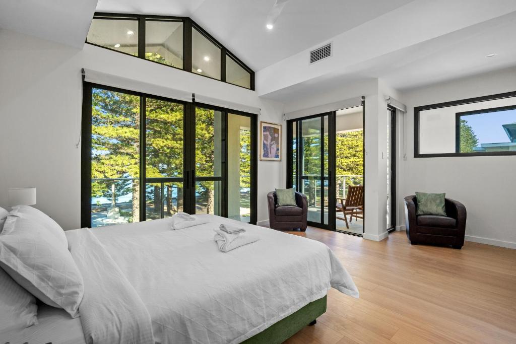 a bedroom with a bed and two chairs and windows at Harborview Modern Apartment 8F in Victor Harbor