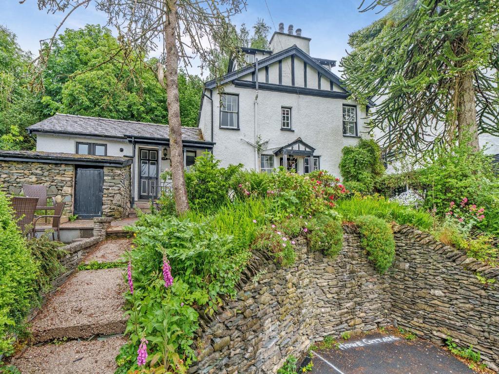 an old house with a stone wall and flowers at Howe Cottage in Bowness-on-Windermere