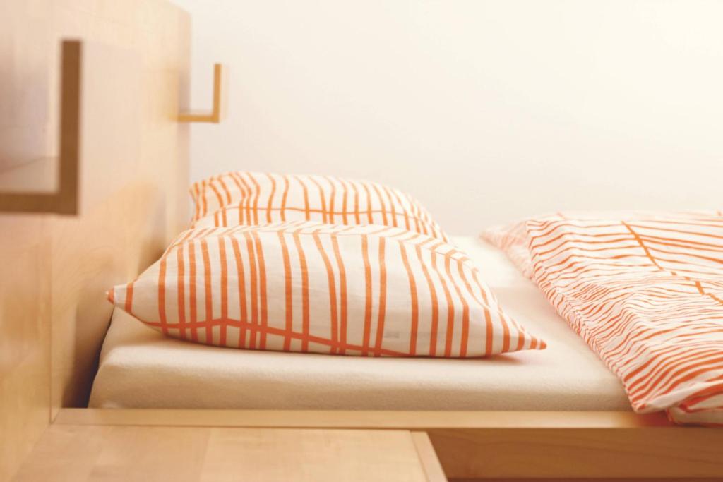 ein Bett mit zwei orangen und weißen Kissen darauf in der Unterkunft Downtown Terrace in Bratislava