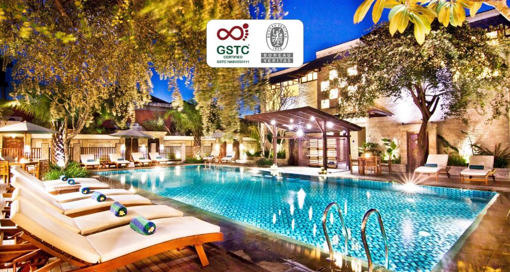 a large swimming pool with lounge chairs next to a building at Best Western Kuta Villa in Kuta