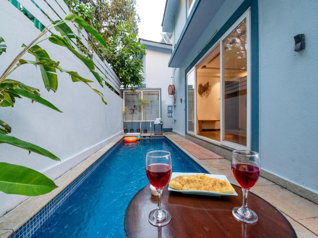 a table with two glasses of wine and a pizza at DanCenter Infinity Villa I 5BHK I Pvt Pool I Baga I GOA in Goa