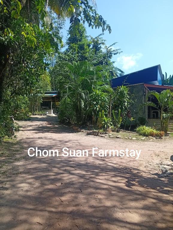 a dirt road in front of a house with trees at Chom Suan Farmstay in Ko Kood