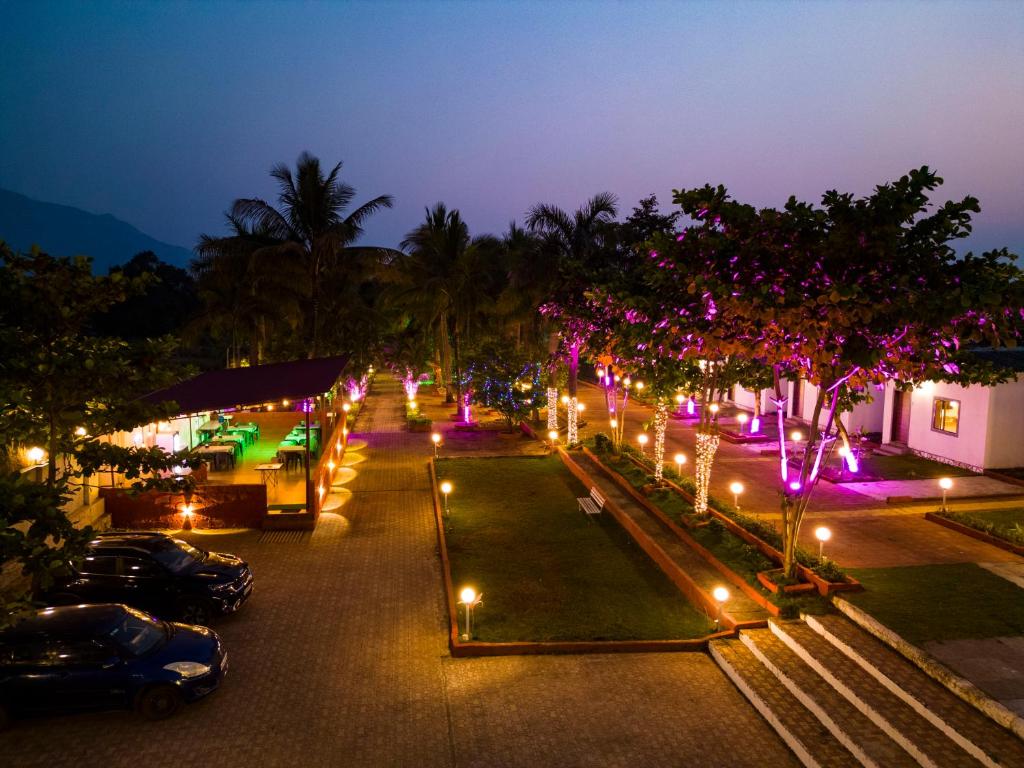 a parking lot with trees and lights at night at Suryavan Holidays in Chinchavli