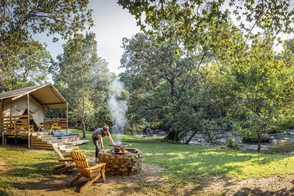 a man standing next to a fire pit in a park at AfriCamps at Mackers 
