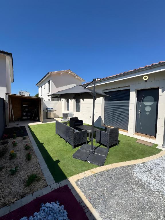 a backyard with a lawn with two chairs and an umbrella at Maison de Vacances Mon Cocon Bordelais in Villenave-dʼOrnon