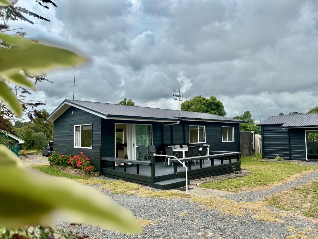 a blue house with a picnic table in front of it at Peaceful Country Escape in Gordonton - Green Meadows Cottage in Taupiri