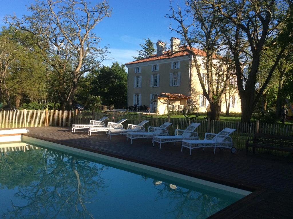 a group of white chairs sitting next to a swimming pool at Lou Castet de Lussolle - Chambres d'hôtes in Losse