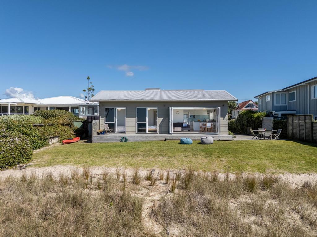 a house on the beach with a yard at Beachfront Beauty - Whangamata Beachfront Home in Whangamata