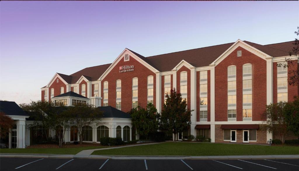 a large red brick building with a lot of windows at Hilton Garden Inn Jackson-Madison in Madison