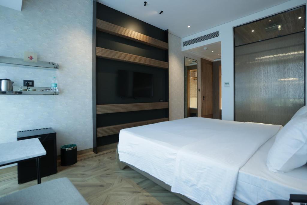 a bedroom with a large white bed and a television at Regency Hotel Malabar Hill in Mumbai