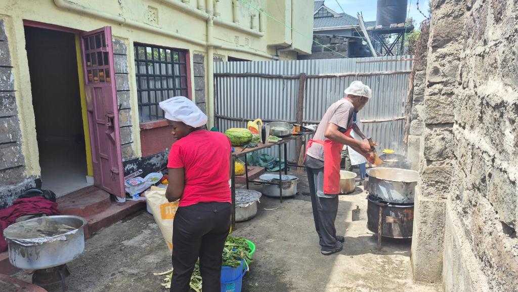 two people are standing outside a building preparing food at Kiwis home in Nakuru
