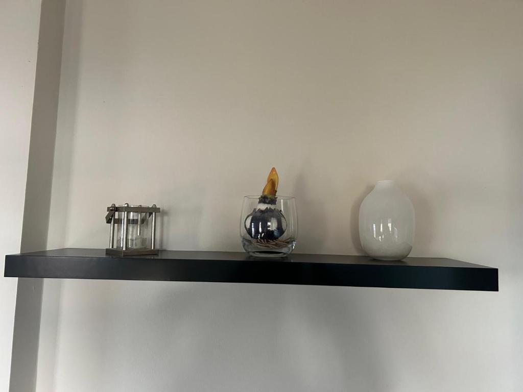 a black shelf with vases and a bottle on it at Ferienwohnung Müritz-Blick in Waren