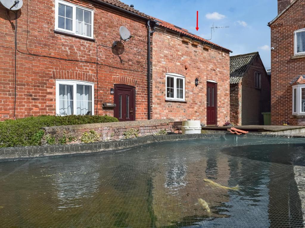 a pool of water in front of a brick building at The Old Dairy in Nether Broughton