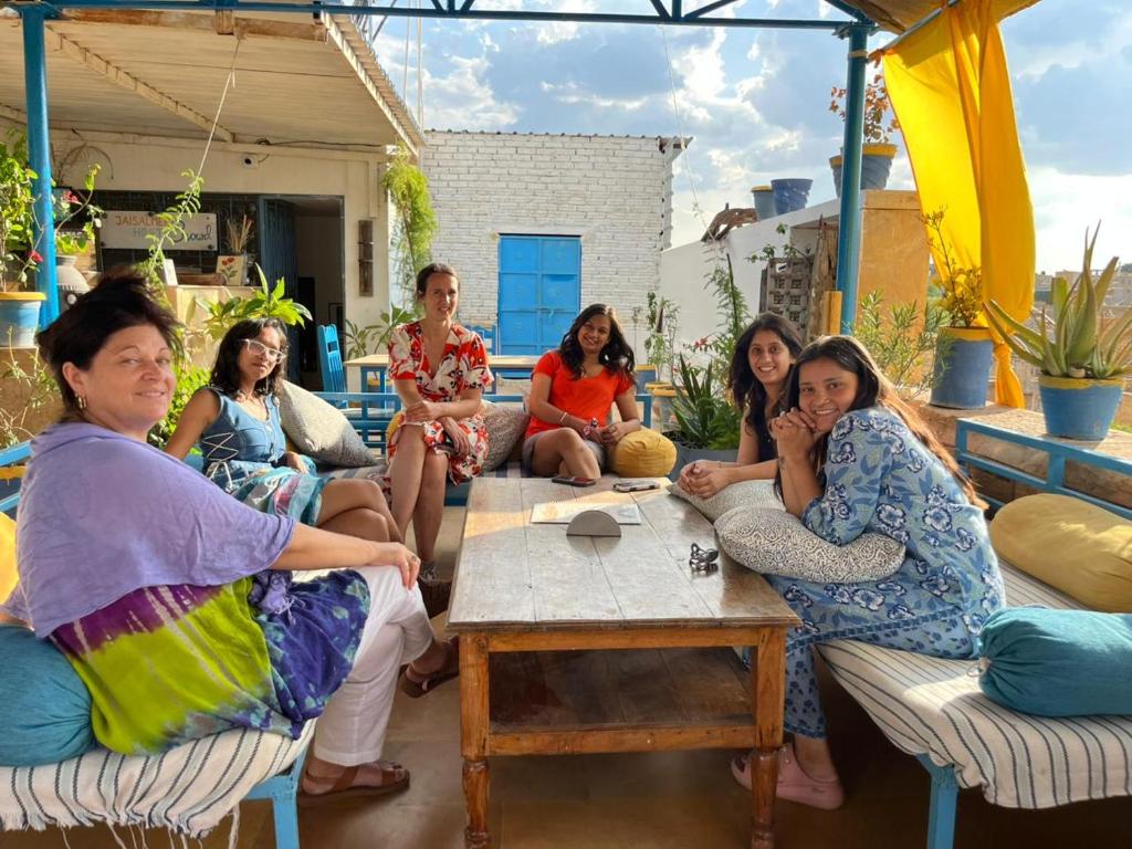 a group of women sitting around a table on a patio at Jaisalmer Hostel Crowd in Jaisalmer