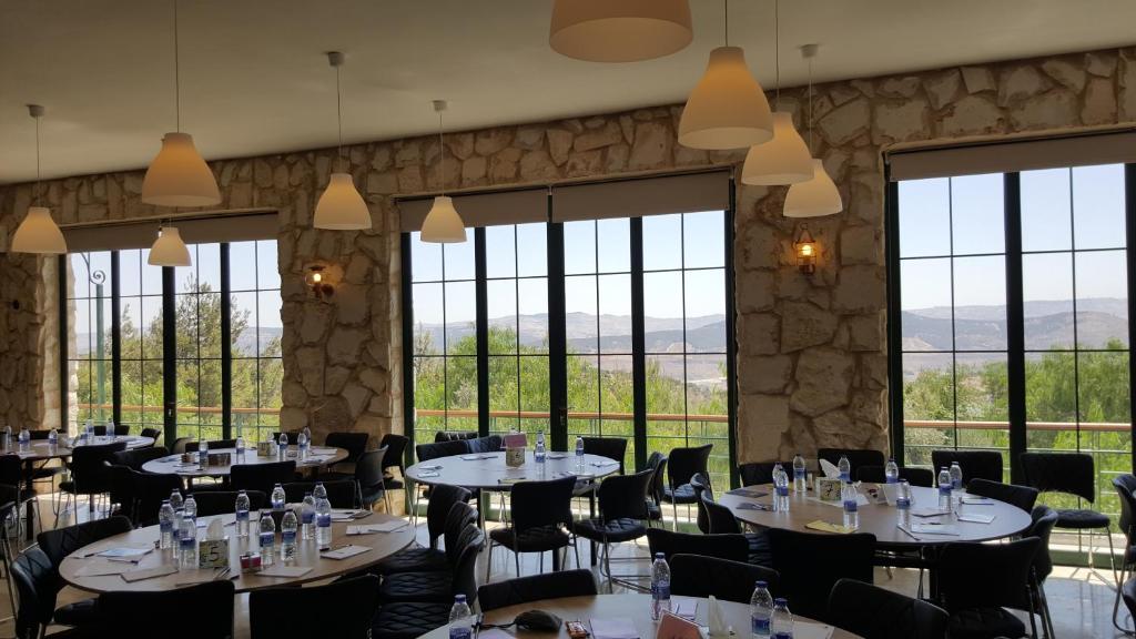 una sala da pranzo con tavoli, sedie e finestre di Mountain Breeze Lodge & Resort ad Al-Salṭ