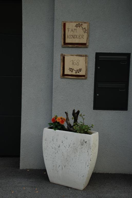 a white planter with flowers in it next to a wall at Ferienwohnung Kendler in Hüttschlag