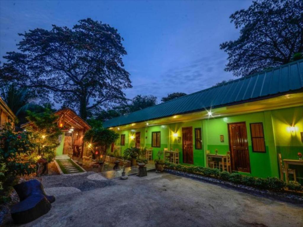 a green building with a yard with tables and chairs at OYO 622 Butterfly Totem Guesthouse in Puerto Princesa City
